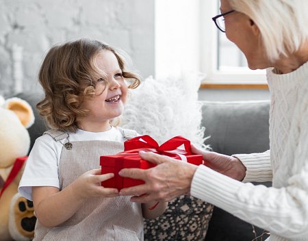Mergaitė Kalėdų proga dovanoja dovaną močiutei